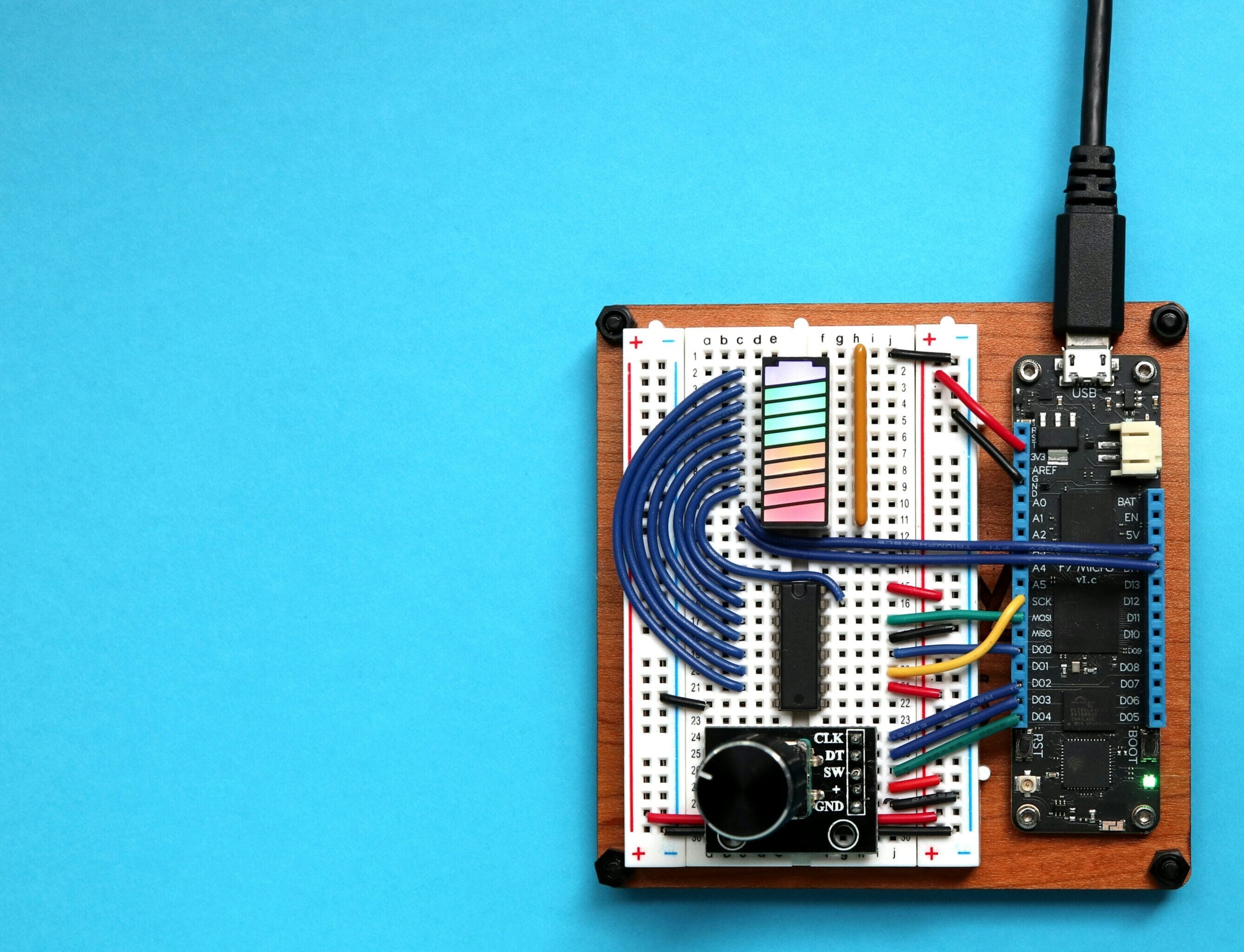 En elektronisk pryl med sladd som är isärplockad så man ser de olika komponenterna. Blå bakgrund